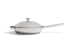 A stainless steel saute pan with a matching glass lid and silver knob, shown from a side angle on a white background with a soft shadow.