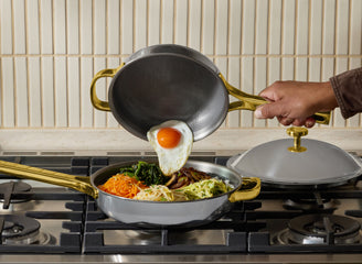 Person cooking eggs and vegetables in a frying pan on a stove