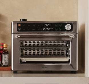 Stainless steel toaster oven on a kitchen counter with digital display