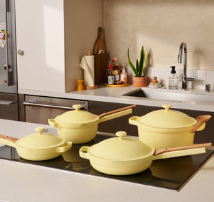 Set of yellow cookware on a kitchen stove with a modern kitchen background.