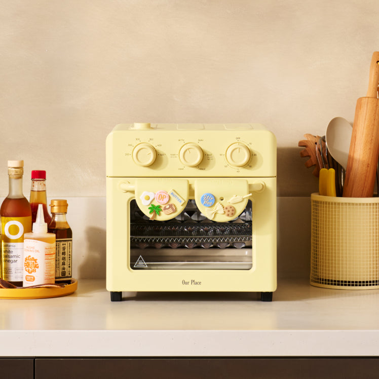Yellow toaster oven on a kitchen counter with various items in the background
