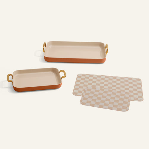 Two rectangular trays with handles and a checkered mat on a white background
