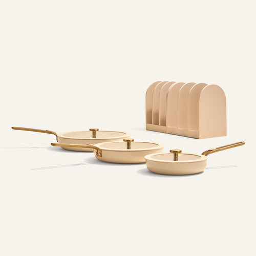 Set of three beige frying pans with gold handles on a white background