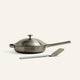 Stainless steel frying pan with lid and spatula on a white background