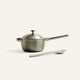 Stainless steel saucepan with lid and spatula on a white background