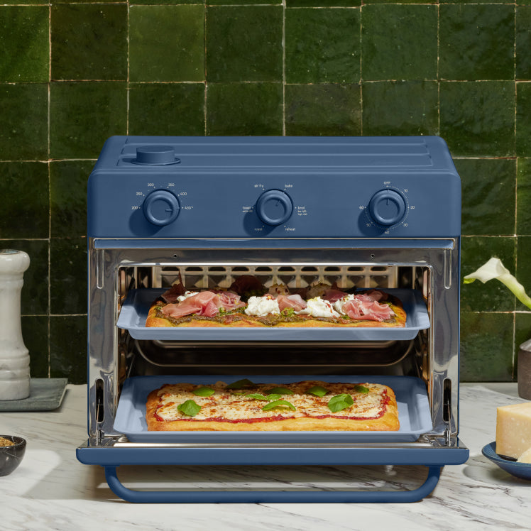 blue large wonder oven on counter cooking pizza on two trays