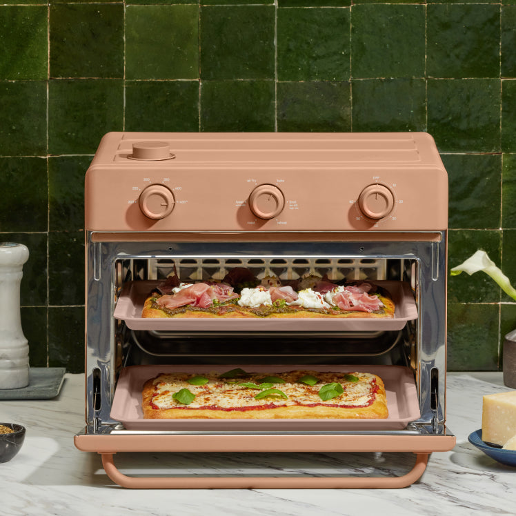 pink large wonder oven on counter cooking pizza on two trays