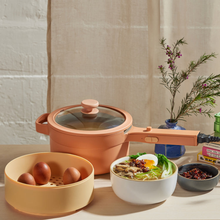 pink perfect power pot with steamer basket and a assortment of food