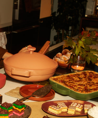 People gathered around a table with food and drinks, including a pot and candles.