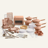 Collection of pink kitchenware including pots, pans, utensils, and cookware on a white background