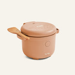A beige Rice Cooker with a digital display features a wooden spatula resting on its lid, set against a plain light background.