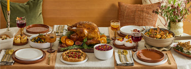Dining table set for a meal with roasted turkey, sides, and drinks.