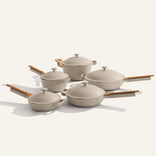 The Cookware Set+ includes five beige nonstick ceramic pieces with wooden handles and lids, beautifully arranged on a plain light background.