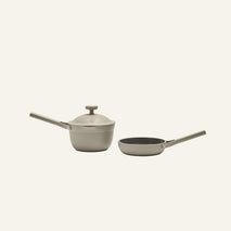 The Tiny Cookware Duo, featuring a beige saucepan with a lid and a matching frying pan, is displayed side by side on a plain light background.