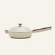 The non toxic ceramic nonstick always pan 2.0, a beige nonstick frying pan from a bestselling cookware set, comes with a matching domed lid, wooden handle, and brass knob, shown against a plain light background.