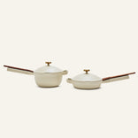 The Mini Cookware Duo—two beige multi-use pans with wooden handles and matching lids—is displayed on a plain light background.